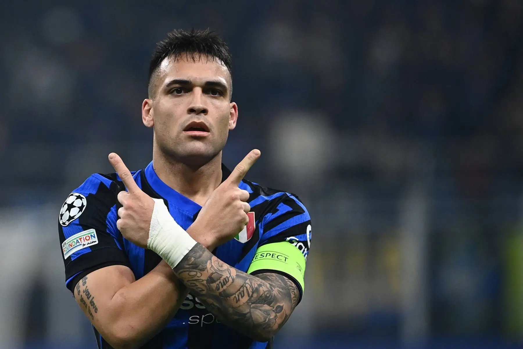 Lautaro Martinez in an Inter Milan jersey crossing his arms and pointing upwards during a match