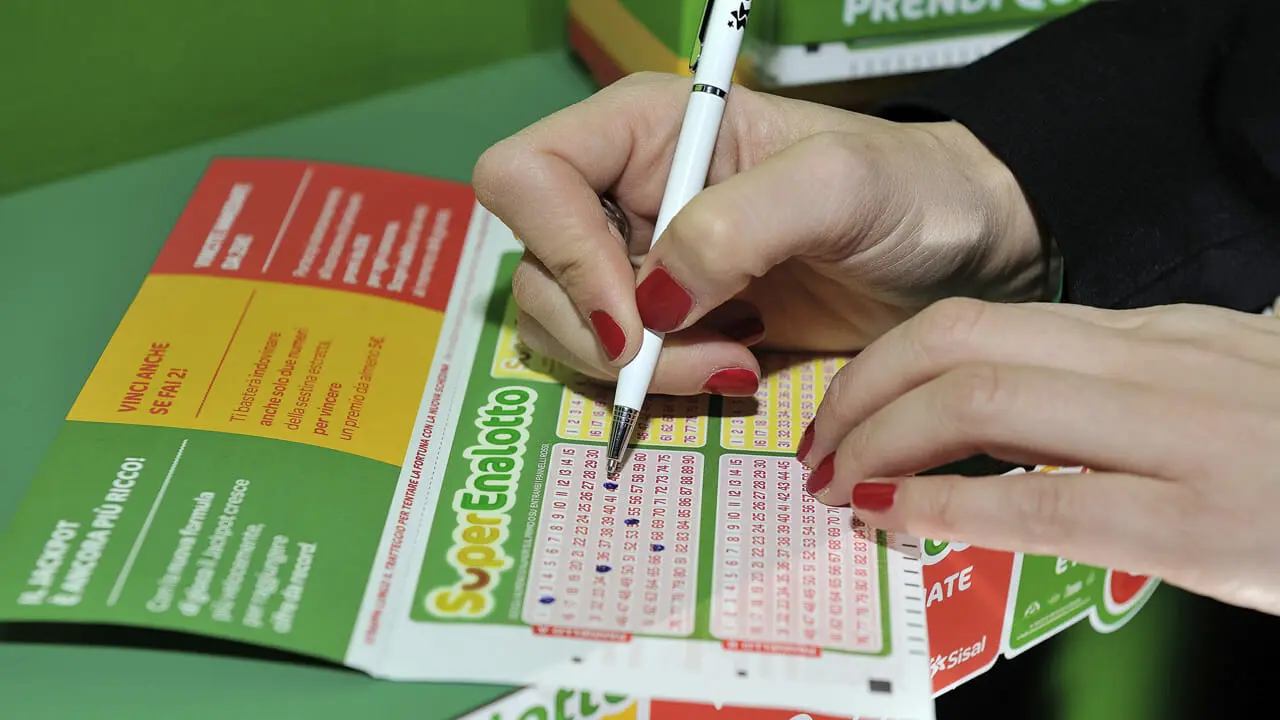 Close-up of a person using a pen to mark numbers on a SuperEnalotto lottery ticket